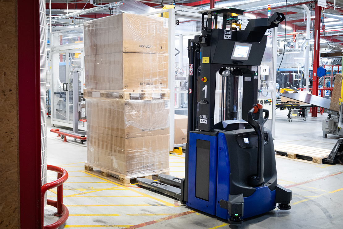 Førerfri AGV gaffeltruck transporterer palle med indpakkede kasser i moderne produktionshal
